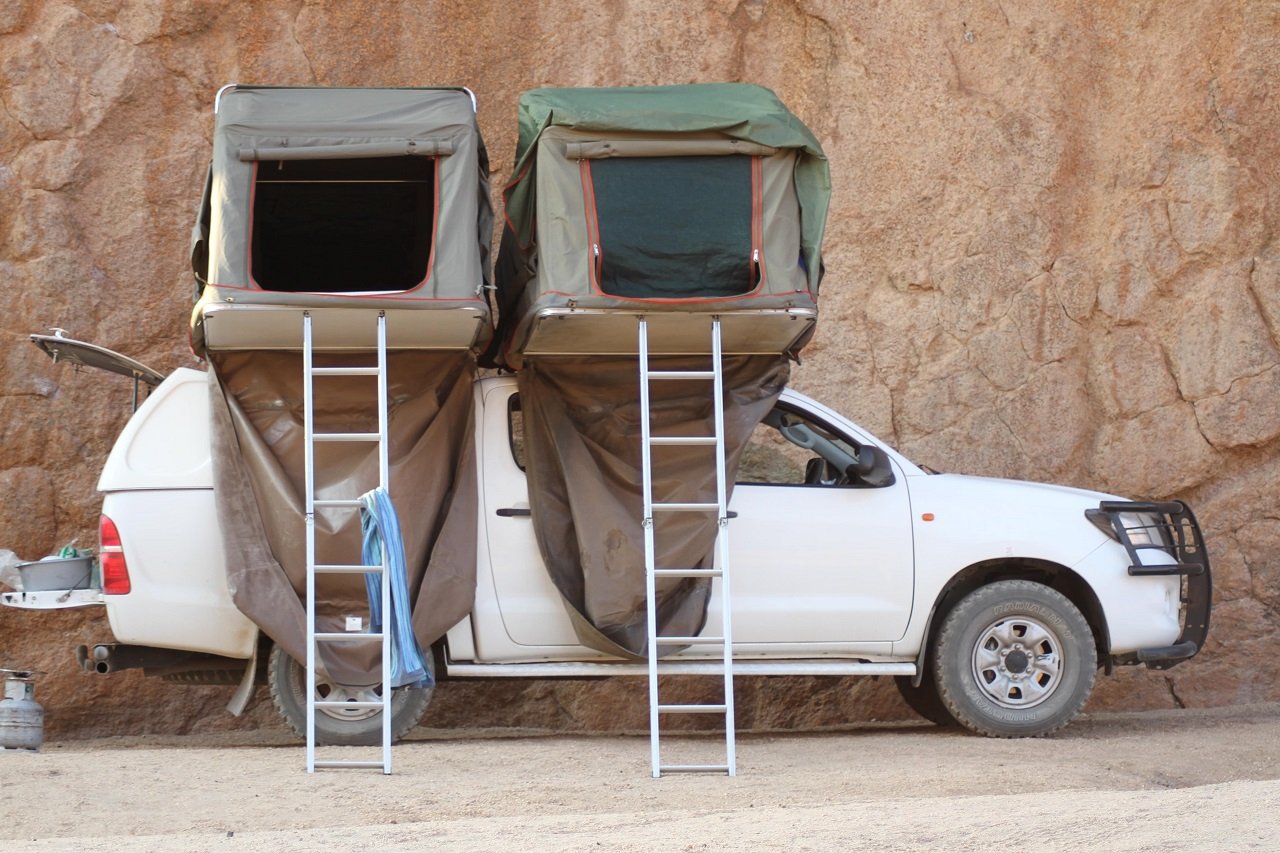 Auto mit Dachzelt vor Felswand - Namibia Highlights