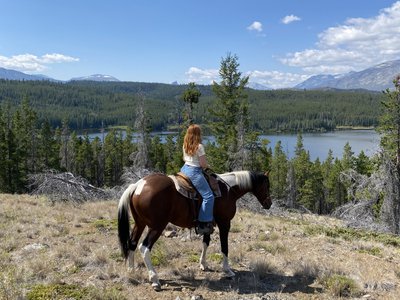 Frau auf Pferd mit Ausblick auf See und Berge - Reisebericht Kanada