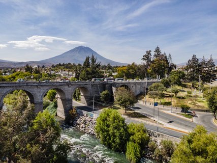 Peru und Bolivien Rundreise – Brücke über Fluss in Arequipa mit Vulkan im Hintergrund