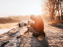 Mann fotografiert im Sonnenuntergang mit großem Objektiv