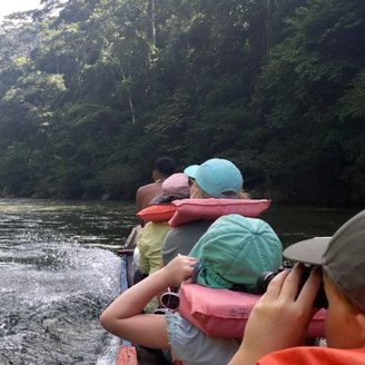 Familie auf Boot in Südamerika, schauen durch fernglas in die ferne auf Fluss - Familienreise