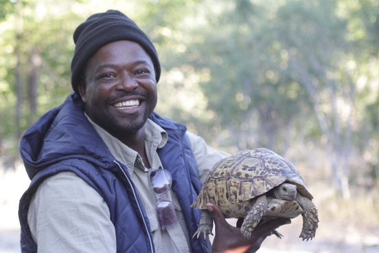 Unser Guide Rex hält eine Schildkröte in den Händen und grinst