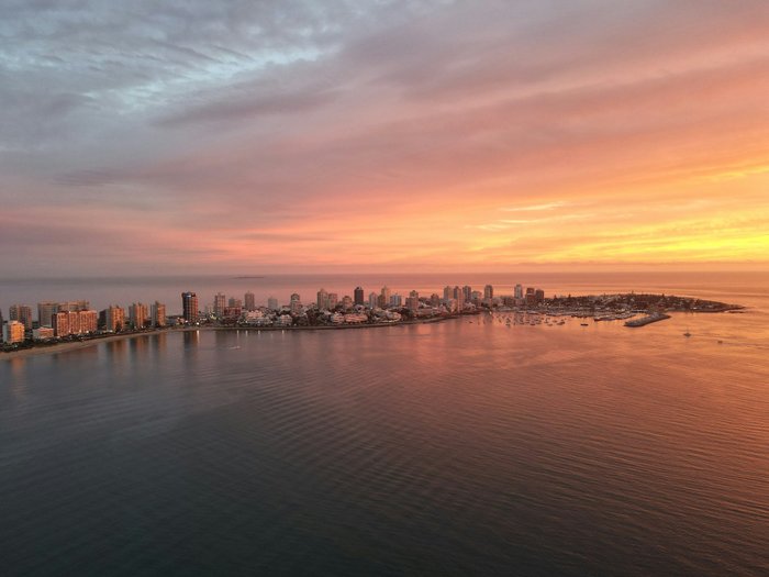 Stadtansicht von Punta del Este mit Hochhäusern an der Küste bei Sonnenuntergang und orange-rotem Himmel