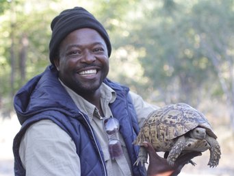 Unser Guide Rex hält eine Schildkröte in den Händen und grinst
