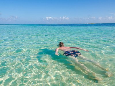 Mann schwimmt im türkisblauen Wasser - Belize Highlights