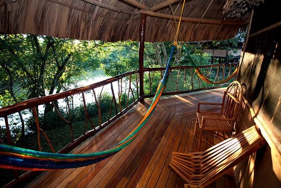 Belize Unterkunft, Baumhaus mit ganz viel Holz und Hängematte ist zusehen in grün