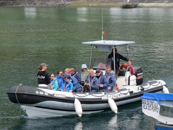 Kleines Boot voller Touristen im Wasser, bereit für die Walbeobachtung