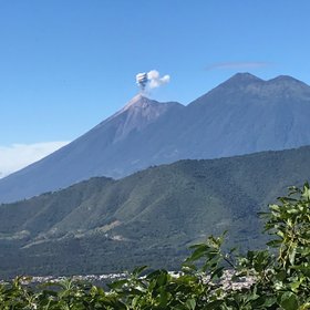 Ausblick auf einem Vulkan der eine kleine Aschewolke ausstößt
