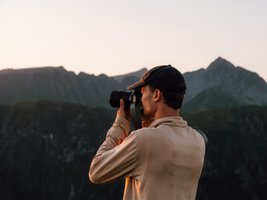 Mann fotografiert das Bergpanorama bei Sonnenuntergang