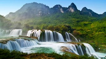 Terrassenförmiger Wasserfall mit Karstbergen im Hintergrund