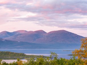 Rosa Wolken über Schwedens Landschaft über einem See und Bergen