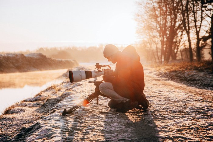 Mann fotografiert im Sonnenuntergang mit großem Objektiv