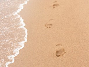 Fußspuren im Sand, bevor eine Welle kommt