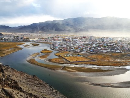 mongolei rundreise 2 wochen fluss mit stadt im hintergrund und bergen 