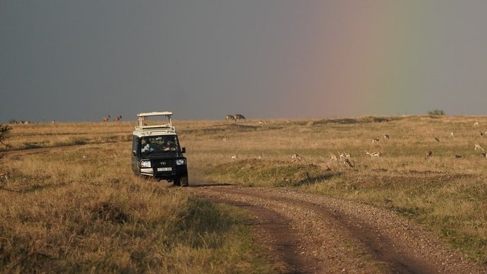 In der Savanne Tansanias leuchtet ein Regenbogen am Himmel