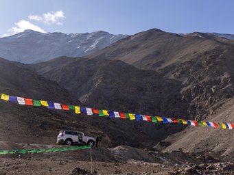 Auto steht am Beghang, davor Gebetsfahnen
