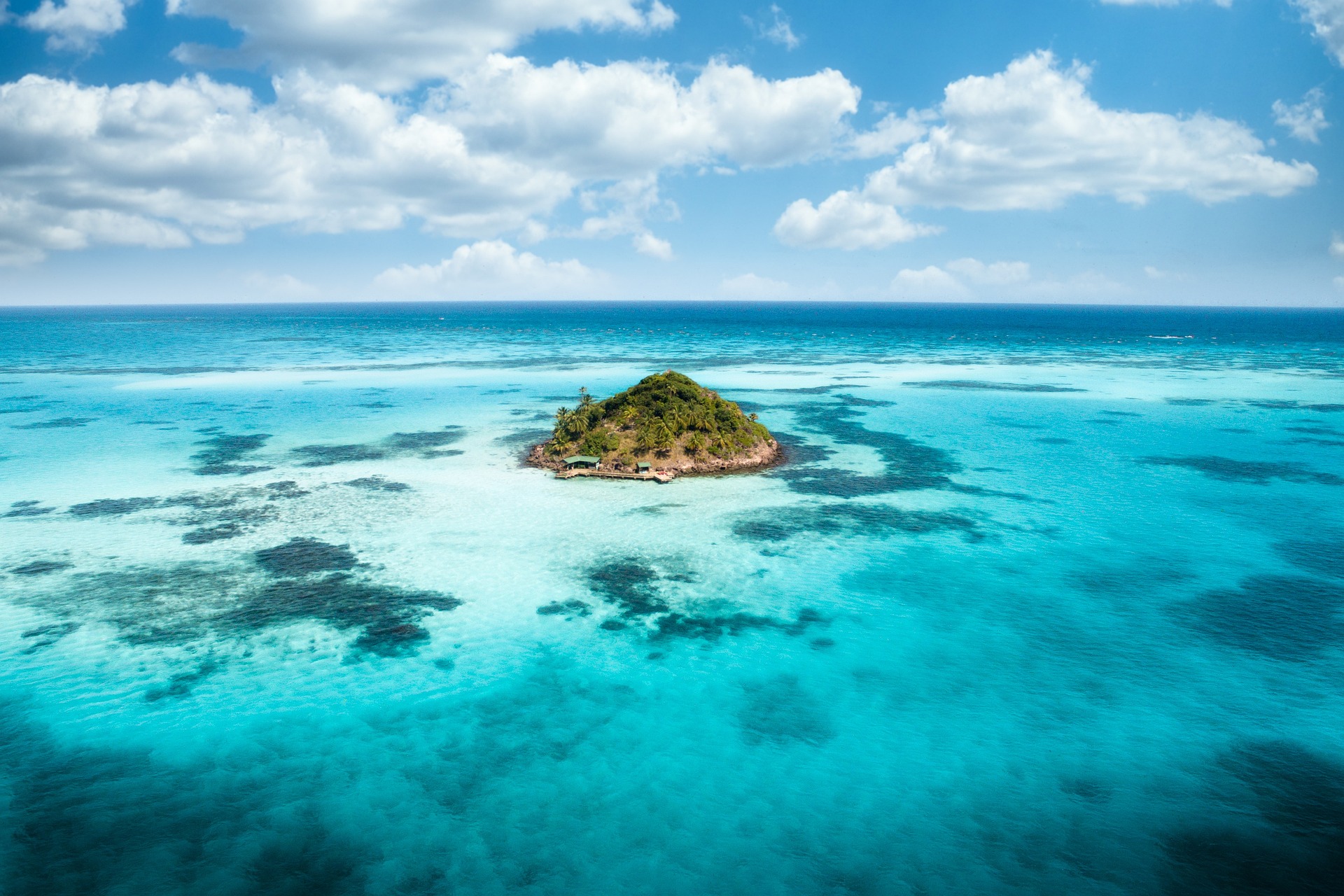 Eine kleine Insel in der Karibik umgeben von kristallklaren Wasser.