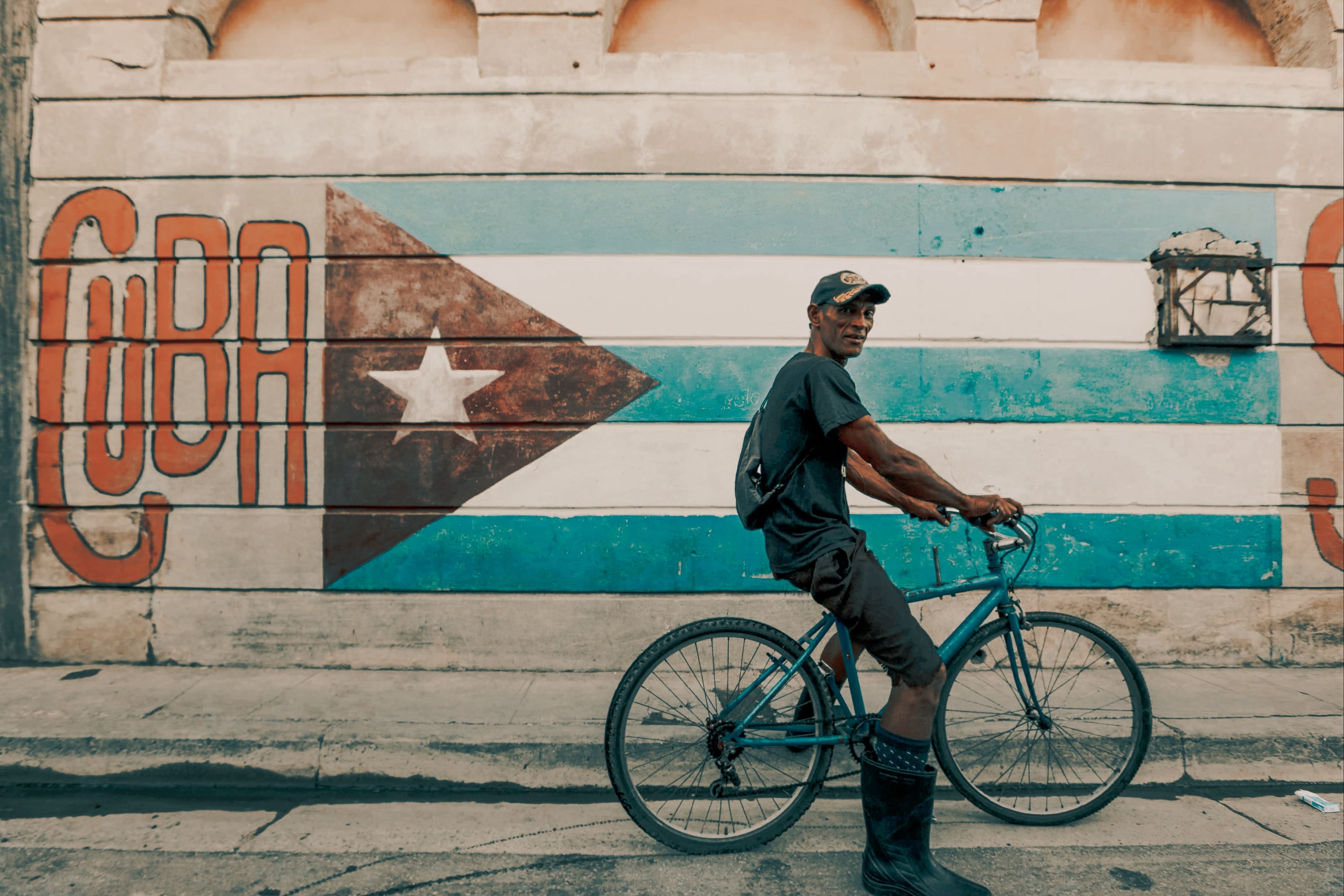 Mann mit Fahrrad posiert für Foto vor Kuba Flagge