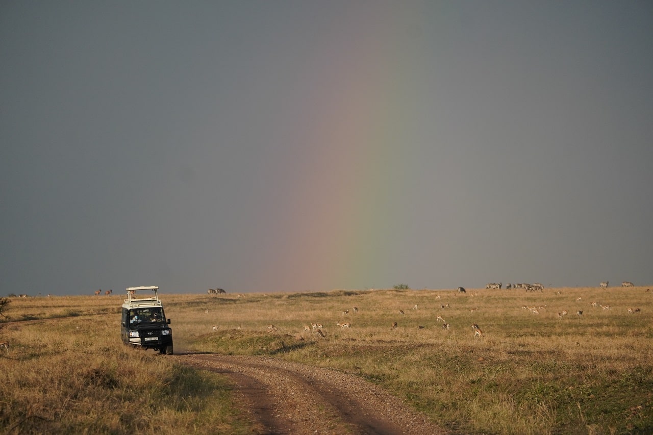 In der Savanne Tansanias leuchtet ein Regenbogen am Himmel