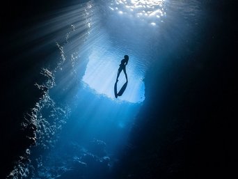 Taucher schwimmt Richtung Licht 