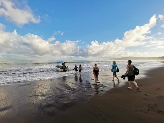 Reisegruppe läuft zu einem Boot am Strand von Corcovado in Costa Rica