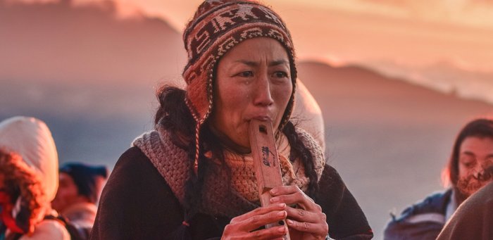 Frau im Sonnenuntergang spielt eine Art Flöte