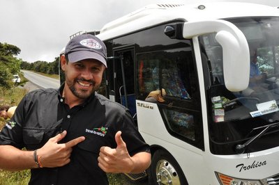 Reiseleiter Jonathan Serrano glücklich vor einem Reisebus