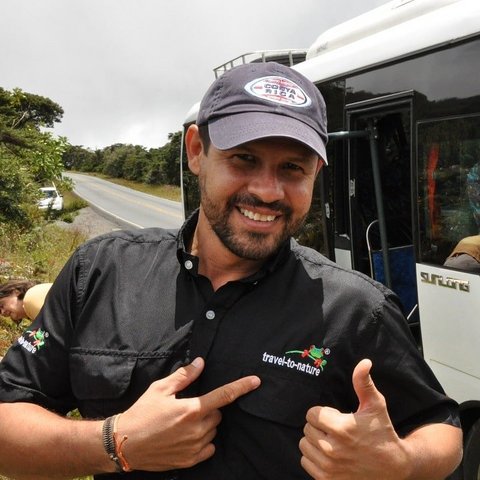 Reiseleiter Jonathan Serrano glücklich vor einem Reisebus