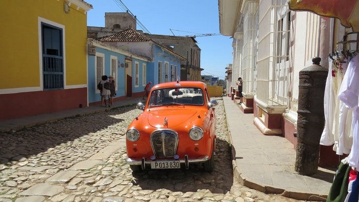 Orangener Oldtimer in einer Straße in Kuba