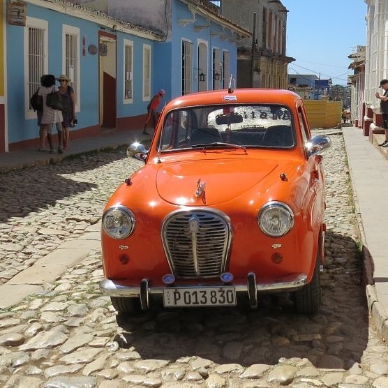 Orangener Oldtimer in einer Straße in Kuba