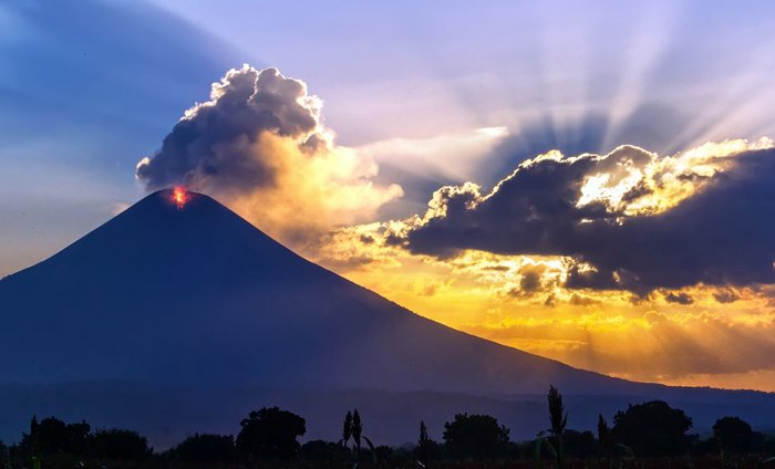 Sonne geht dramatisch hinter einem Vulkan unter