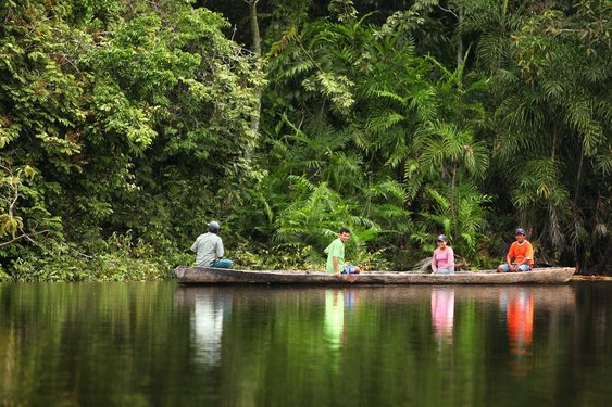 Einheimische auf einem langen Floß auf einem Fluss