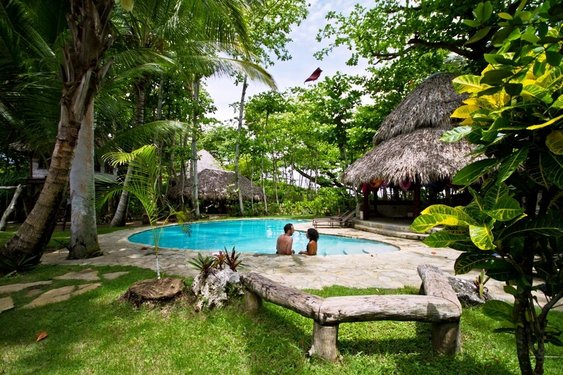 Zwei Menschen am Pool im Garten des Hotels Natura Cabana