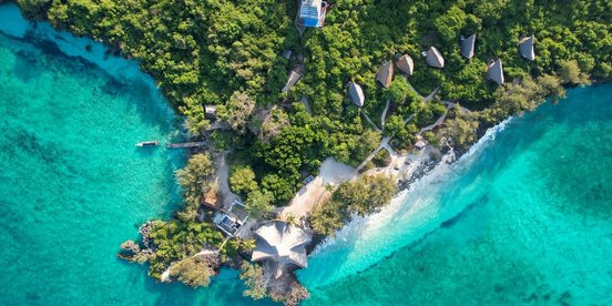 Insel der Chumbe Island Lodge von oben mit türkisfarbenem Meer und kleinen Hütten