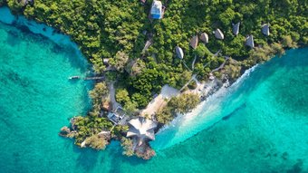 Insel der Chumbe Island Lodge von oben mit türkisfarbenem Meer und kleinen Hütten