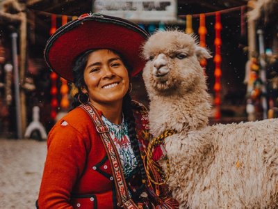 Lachende peruanische Frau mit einem Lama