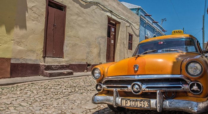 Orangener Oldtimer in einer Gasse in Trinidad