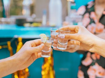 Menschen stoßen mit Tequila an