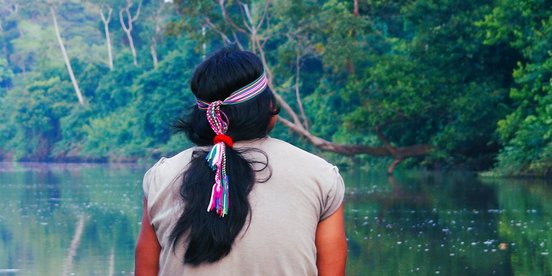 Ecuador Achuar Indianer mit Haarschmuck schaut auf einen Fluss im Amazonas