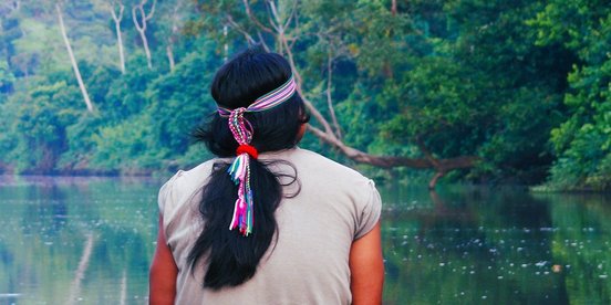 Ecuador Achuar Indianer mit Haarschmuck schaut auf einen Fluss im Amazonas