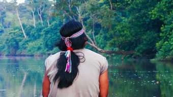 Ecuador Achuar Indianer mit Haarschmuck schaut auf einen Fluss im Amazonas