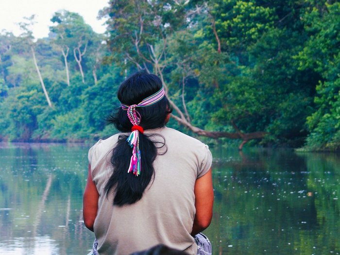 Ecuador Achuar Indianer mit Haarschmuck schaut auf einen Fluss im Amazonas