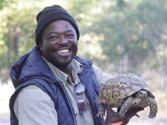 Unser Guide Rex hält eine Schildkröte in den Händen und grinst