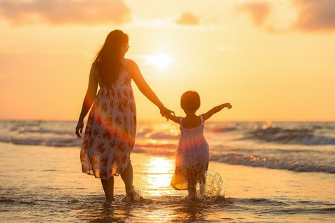 Mutter mit ihrer kleinen Tochter am Strand bei Sonnenuntergang