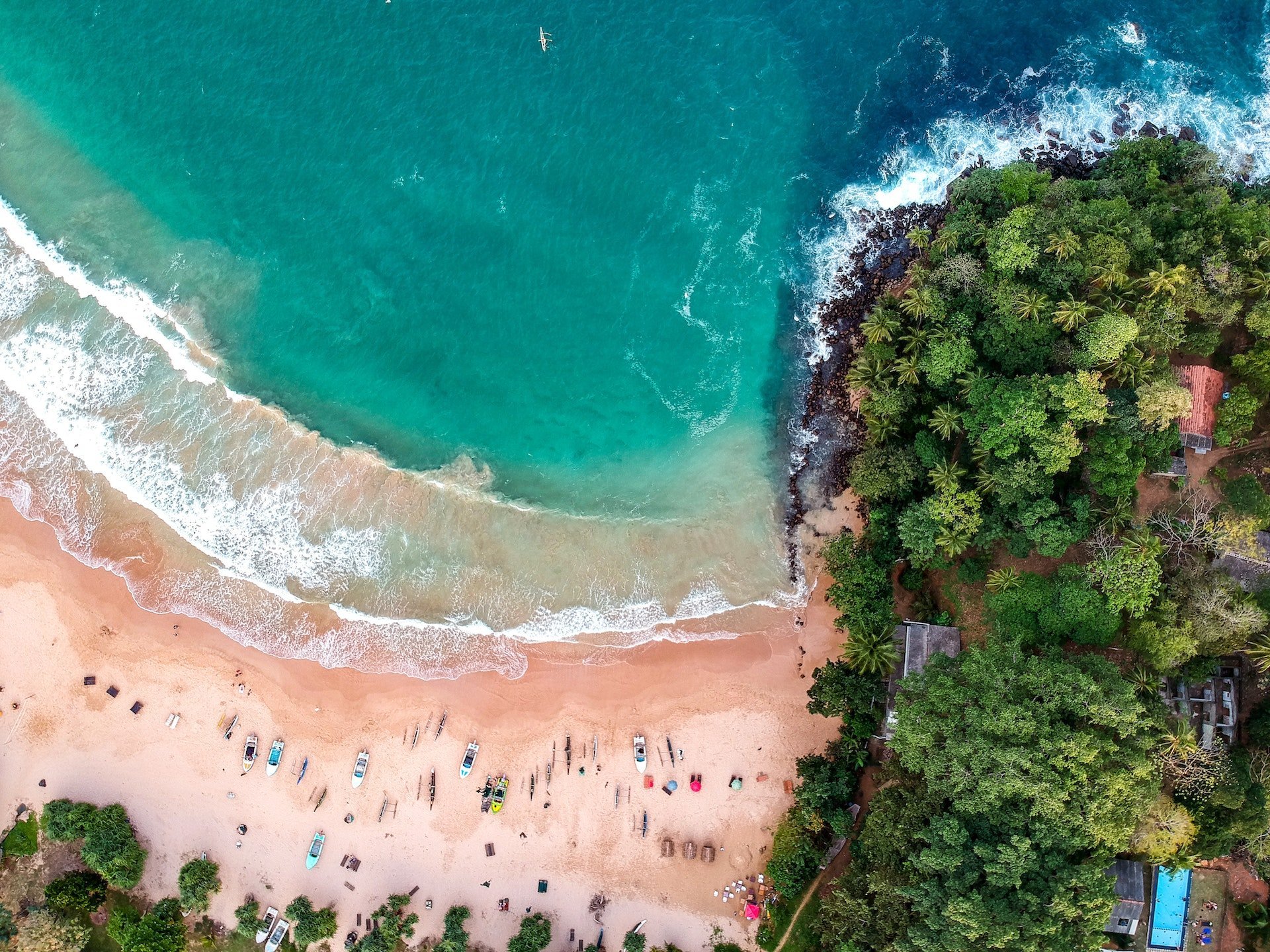 Strand mit Booten und Wald von oben 