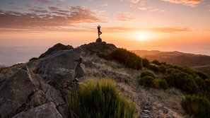 Mensch macht Yoga bei Sonnenaufgang auf einem Berg