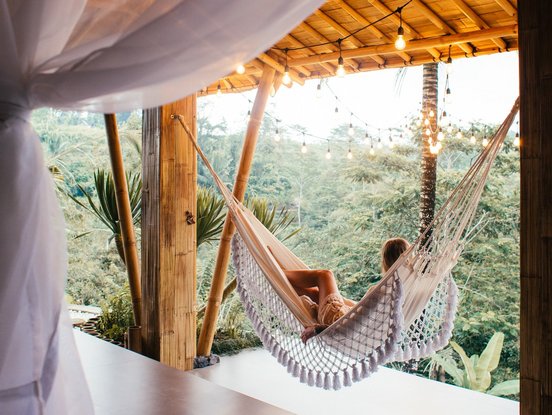 Frau liegt in einer Hängmatte und schaut in den Dschungel