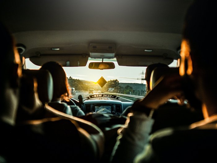 Menschen in einem Fahrzeug bei Sonnenuntergang
