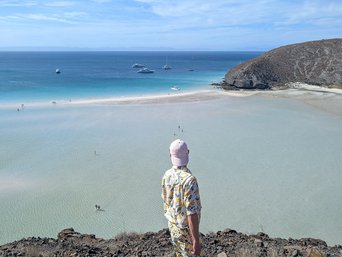 Ein Mann schaut sich von einer anhöhe aus das türkisene Wasser des Playa Balandras an
