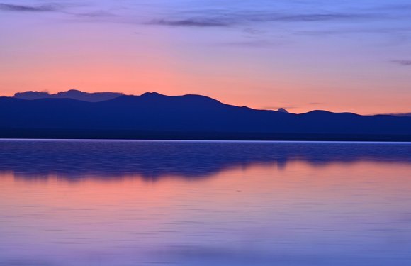 Sonnenuntergang hinter Bergen an einem See in Bolivien